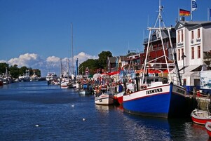 Um porto com barcos atracados, incluindo um barco 'JASMUND' em destaque.