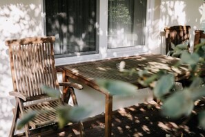 A wooden table and two chairs in a sunlit room with a view of trees outside. - Gut Gremmelin (Lalendorf)