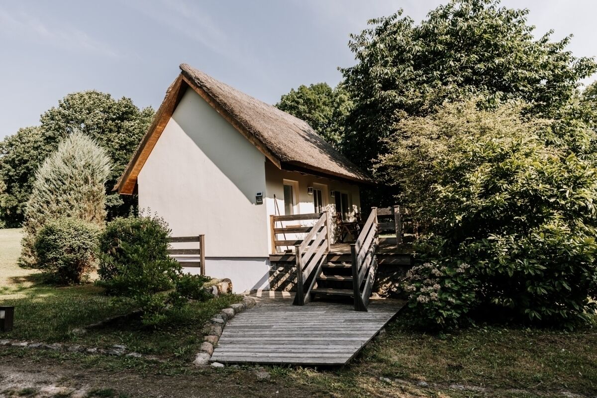 Ein rustikales Gebäude mit einem Strohdach, einer Holztreppe und einer kleinen Veranda.