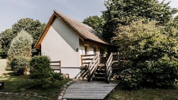 Ein rustikales Gebäude mit einem Strohdach, einer Holztreppe und einer kleinen Veranda.