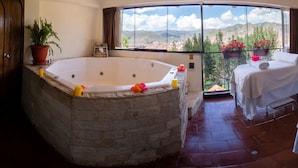 A spa room with a stone bathtub, two massage tables, and a balcony with a city view. - Encantada Casa Boutique Spa (Cusco)