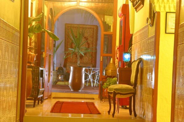 A hallway with a large vase, a chair, and a rug.