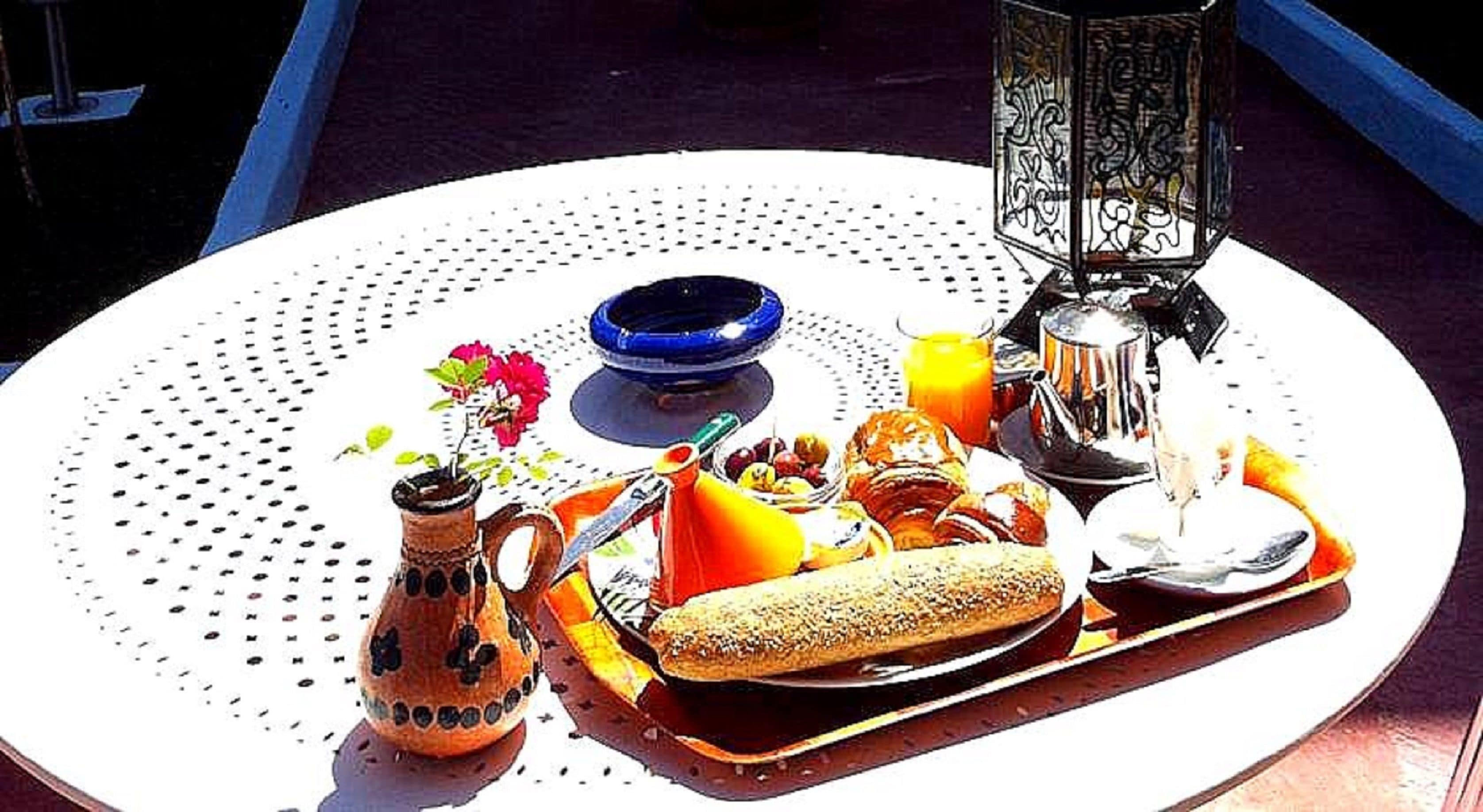 A round table with a white surface and a decorative border, holding a variety of food items and a drink.