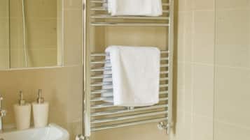 A bathroom with a sink, a mirror, a towel rack with two towels, and a bathtub.