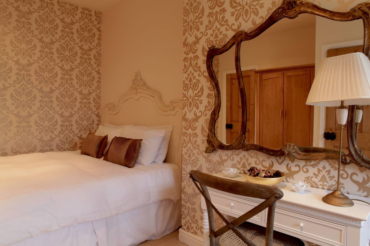 A bedroom with a bed, a dresser, a mirror, and a lamp.