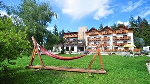 A hotel with a wooden facade, balconies, and outdoor seating. - Hotel Rifugio Sores (Predaia)