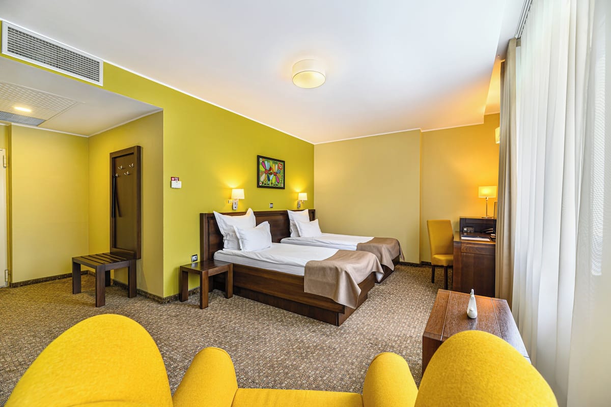 A hotel room with a large bed, two bedside tables, a chair, and a desk.