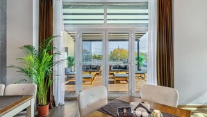 Une chambre d’hôtel moderne avec un coin repas, une plante en pot et une vue sur l’espace extérieur aménagé pour les clients.