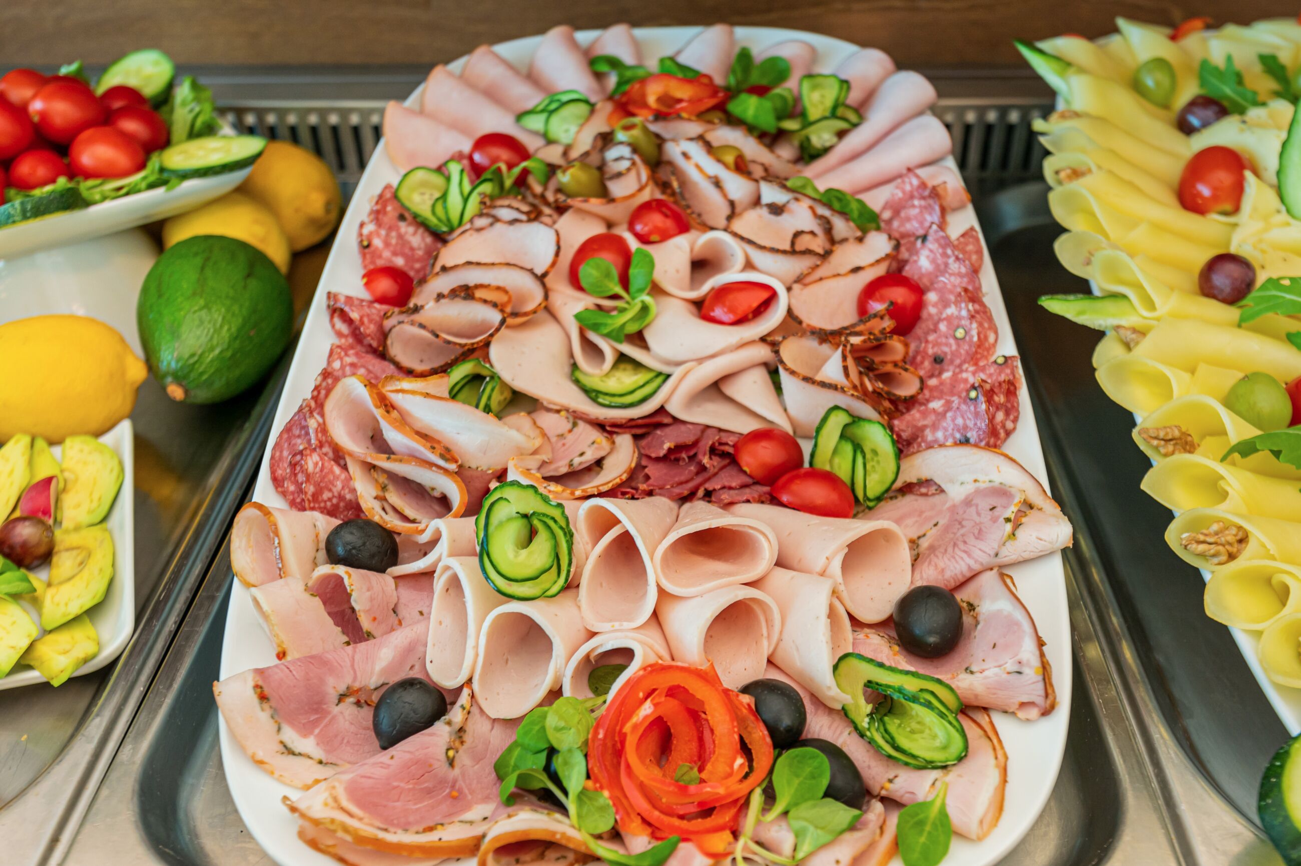 A buffet with various meats, cheeses, and vegetables.