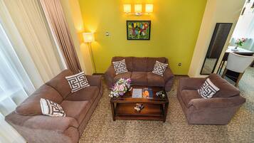 Una sala de estar con dos sofás marrones, una mesa de centro y un arreglo floral.