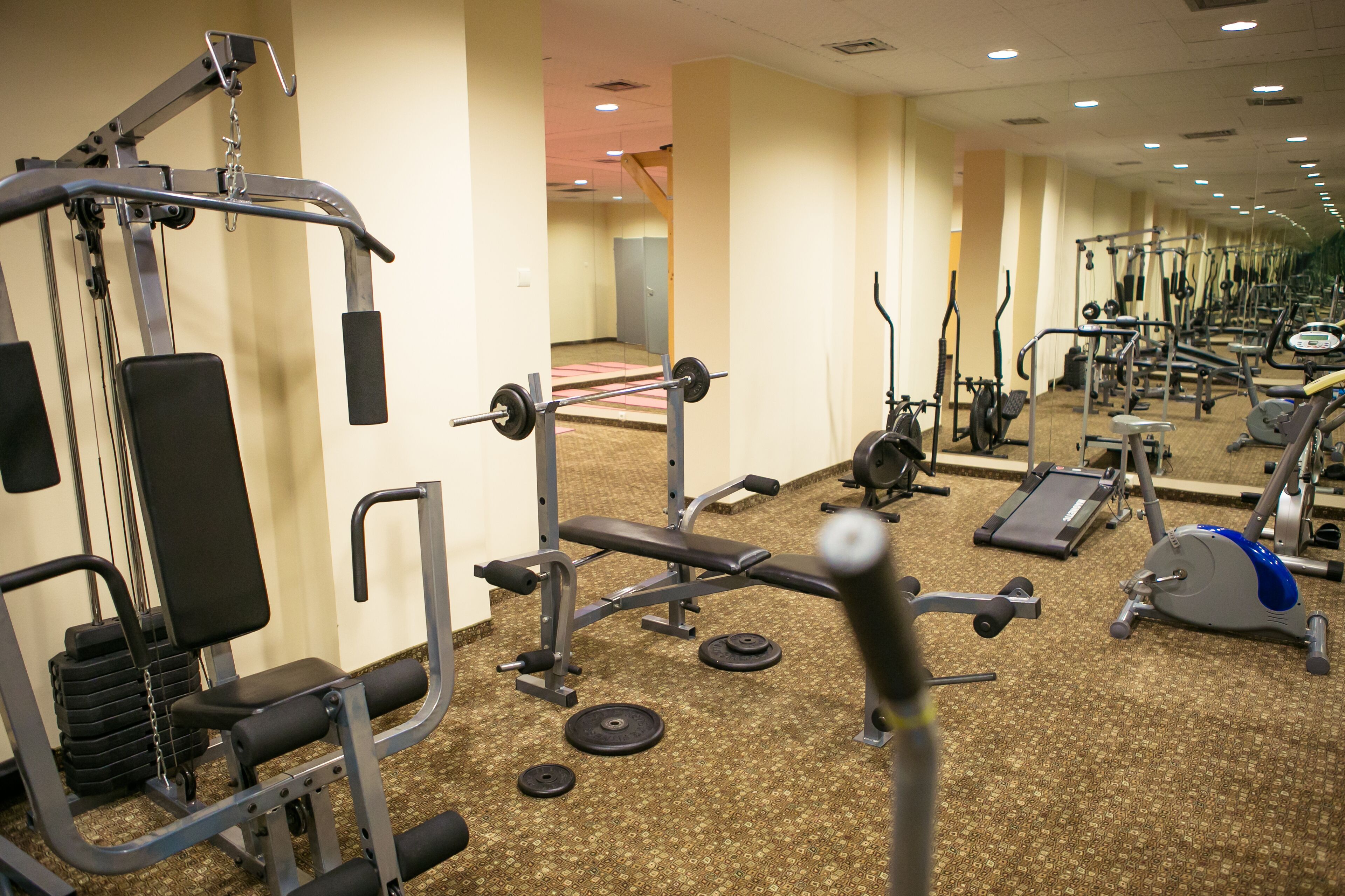 A gym with various exercise equipment, including weight machines, treadmills, and stationary bikes.