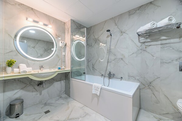A modern bathroom with a marble floor, a large round mirror, a glass-enclosed shower, and a built-in sink. - Vega Hotel (Galati)