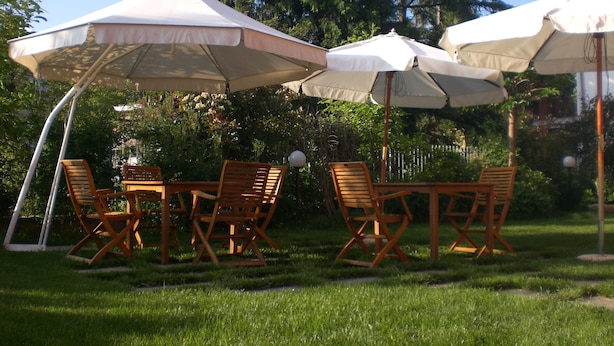 An outdoor seating area with wooden tables and chairs under large umbrellas.