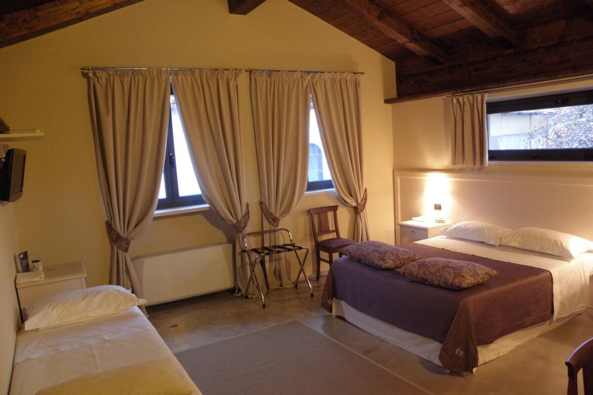 A bedroom with a bed, a chair, a desk, and a radiator.
