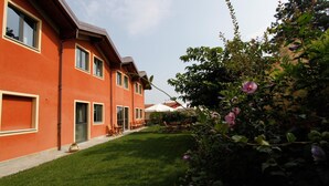 A red building with multiple windows and doors, a well-maintained lawn, and outdoor furniture.
