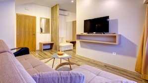 A modern living room with a sofa, a small table with a bowl, a TV on a shelf, and a wooden door. - Villa Cardak (Mostar)