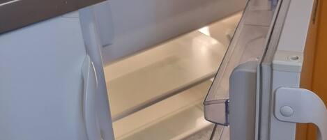 A compact refrigerator with a freezer drawer, a control panel, and a handle.