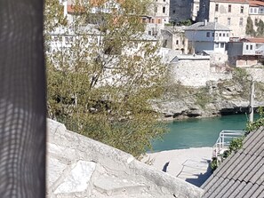 A coastal town with stone buildings, a clear view of the sea, and a rocky shoreline.