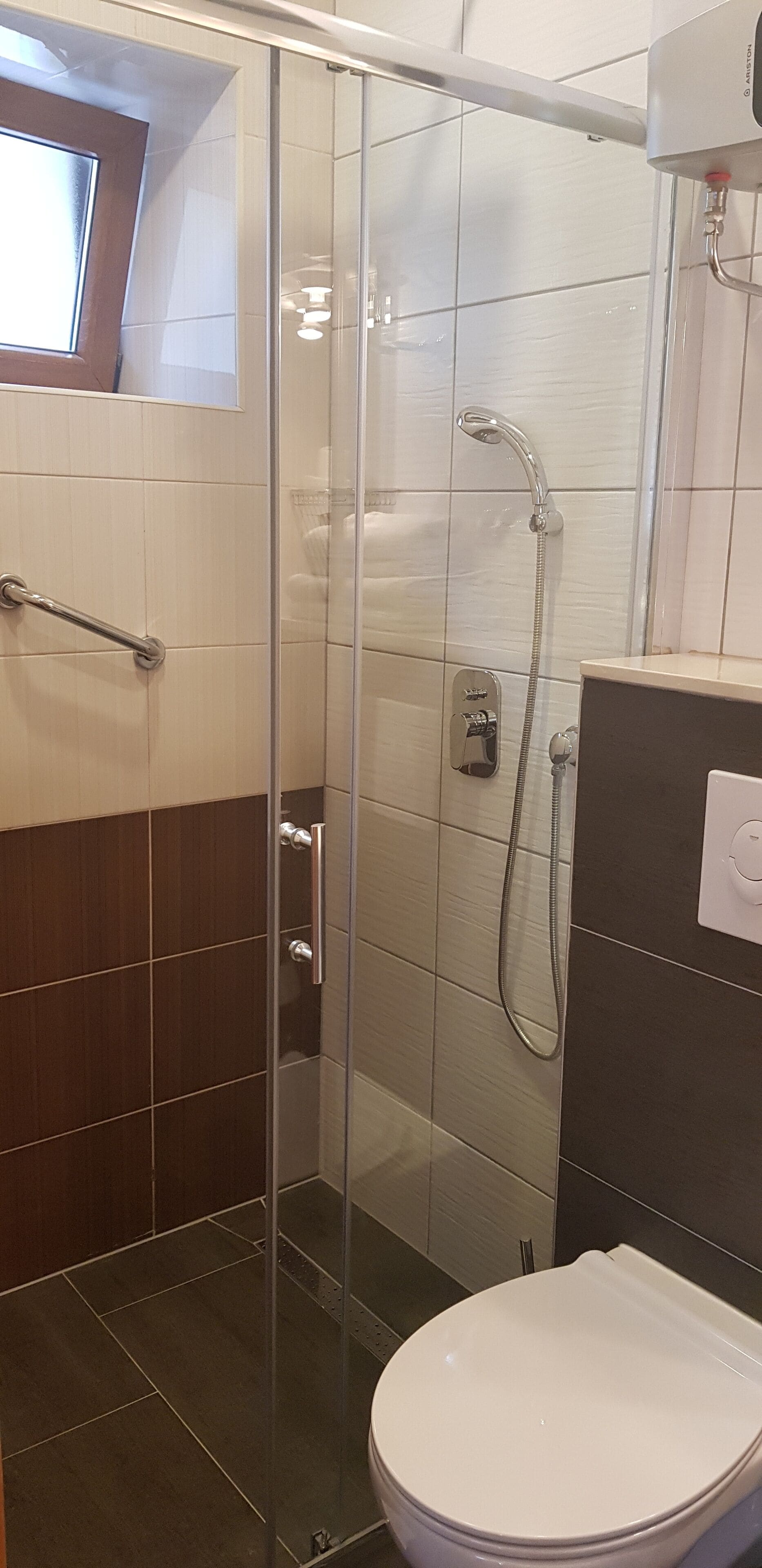 Uma casa de banho moderna com cabine de duche em vidro, sanita e lavatório.