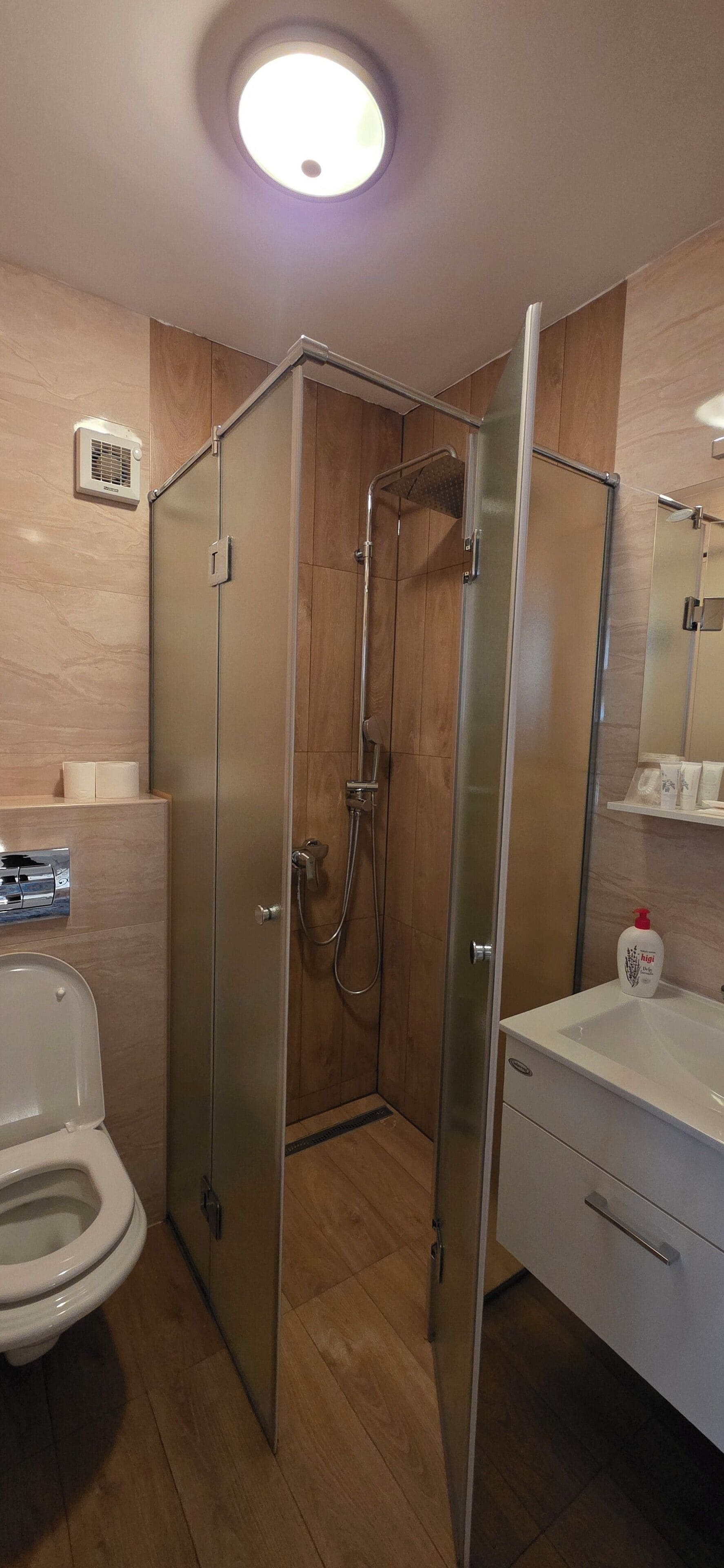 Een moderne badkamer met een douchecabine van glas, een toilet en een wastafel met spiegel.