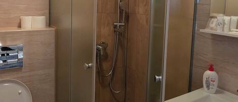 Een moderne badkamer met een douchecabine van glas, een toilet en een wastafel met spiegel.