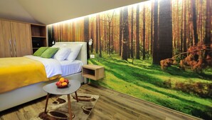 A modern bedroom with a large bed, a nightstand, a small table with fruit, and a forest mural on the wall. - Villa Cardak (Mostar)