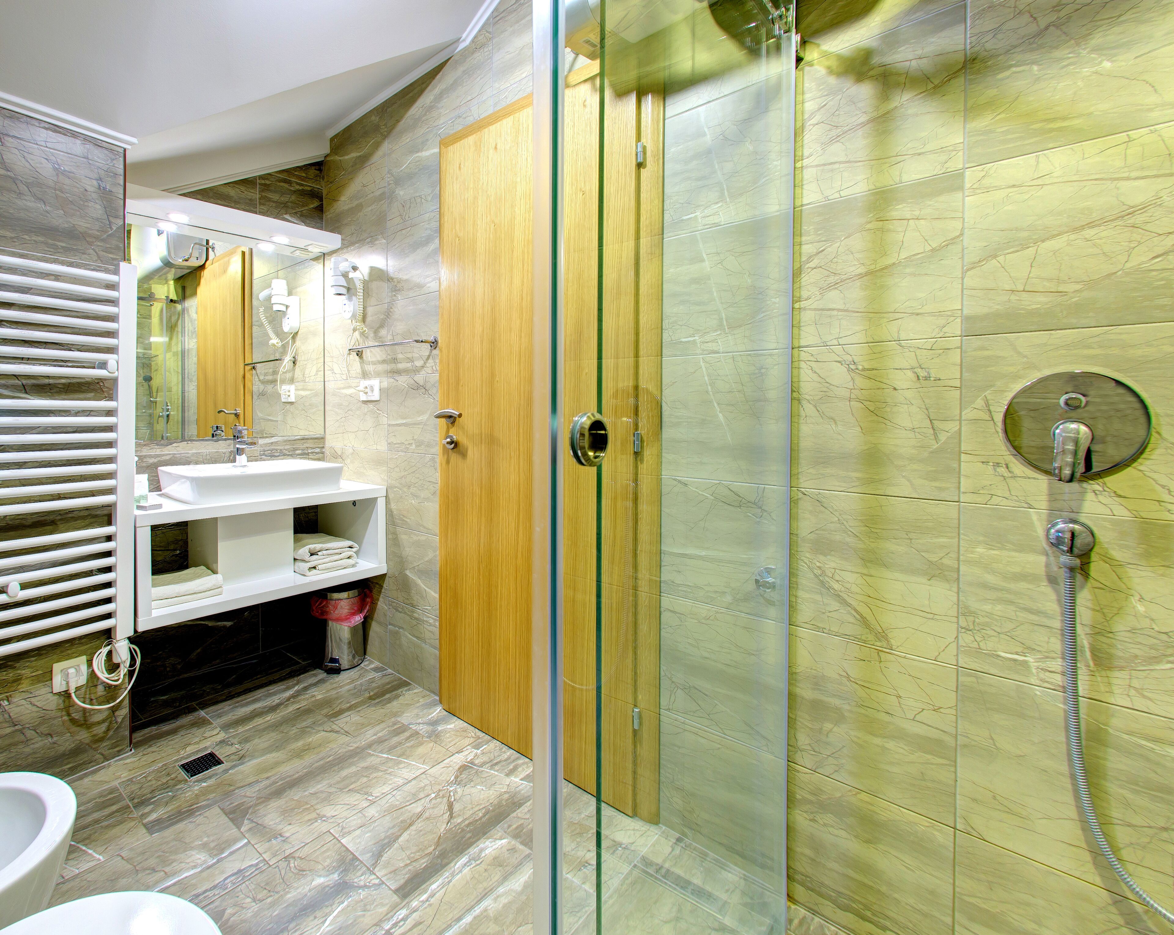 A modern bathroom with a glass-enclosed shower, a white sink, and a wooden vanity.