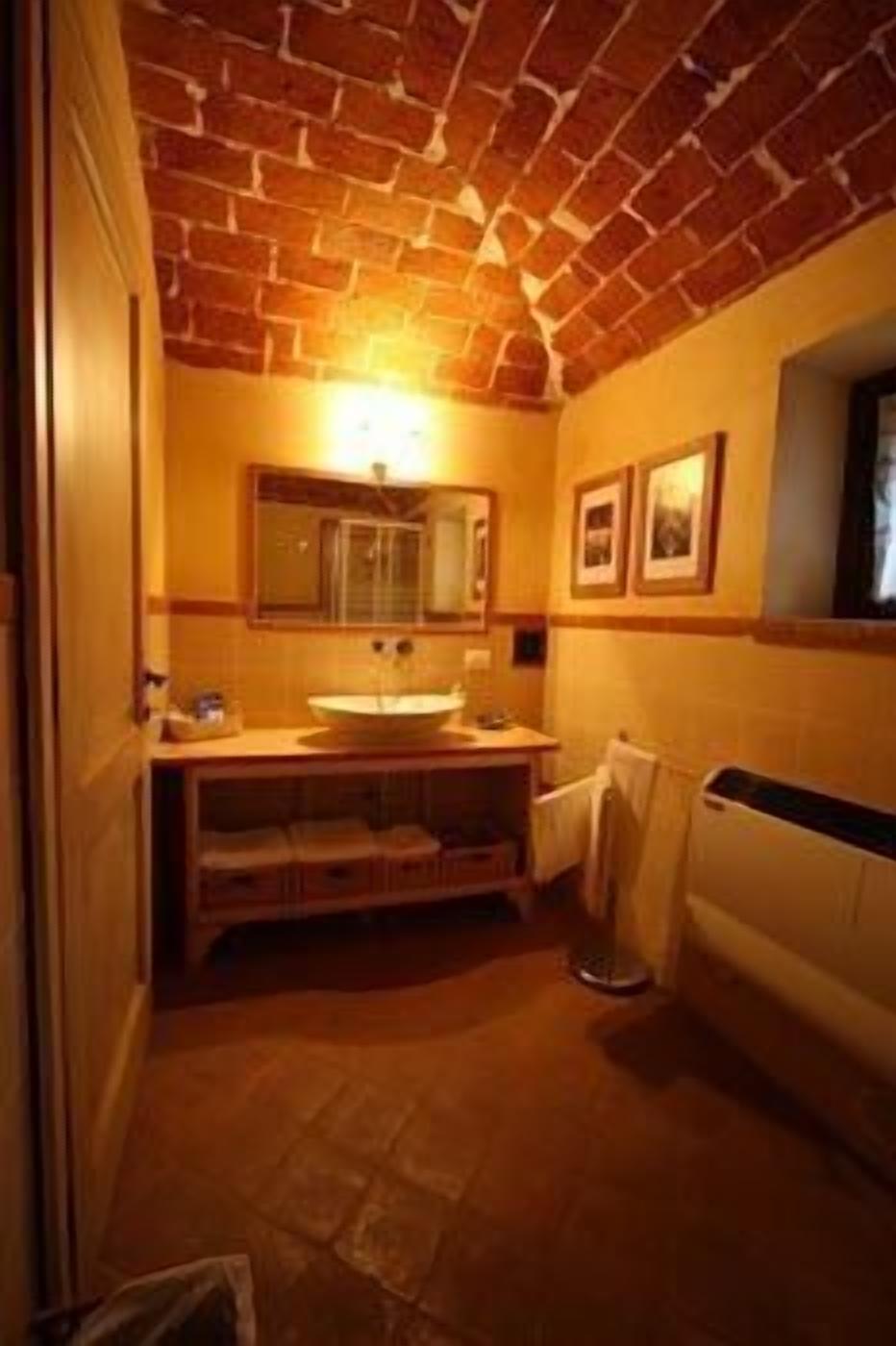 A bathroom with a brick ceiling, a sink, a mirror, and a radiator.