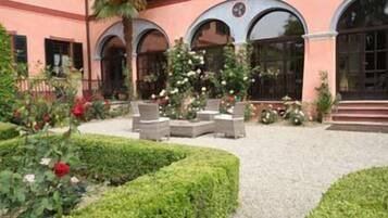 Un patio con zona de estar, una fuente y setos bien cuidados.