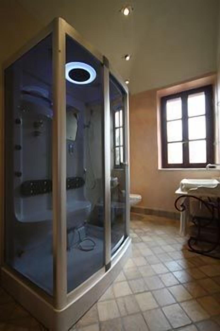 A bathroom with a glass-enclosed shower, a toilet, and a sink.