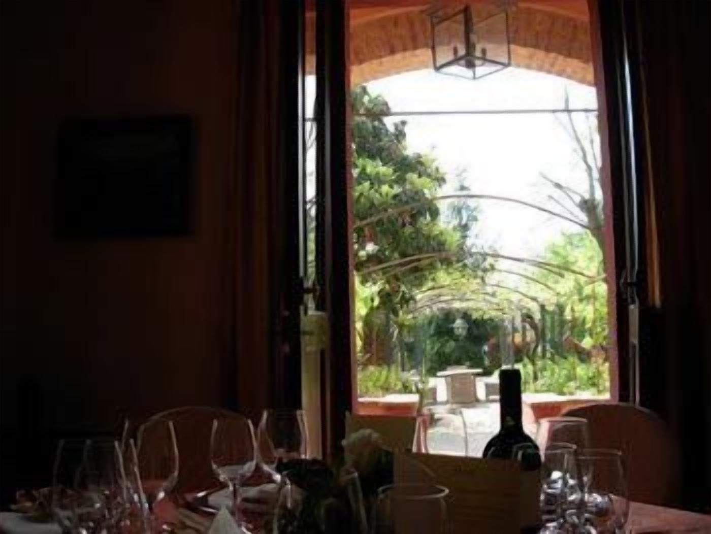 A dining area with a table set for two, a bottle of wine, and empty wine glasses.