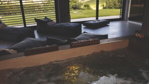 Un jacuzzi con vistas a un paisaje verde a través de amplios ventanales.