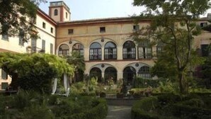 Un patio con un edificio que tiene ventanas de arco y una fuente central.
