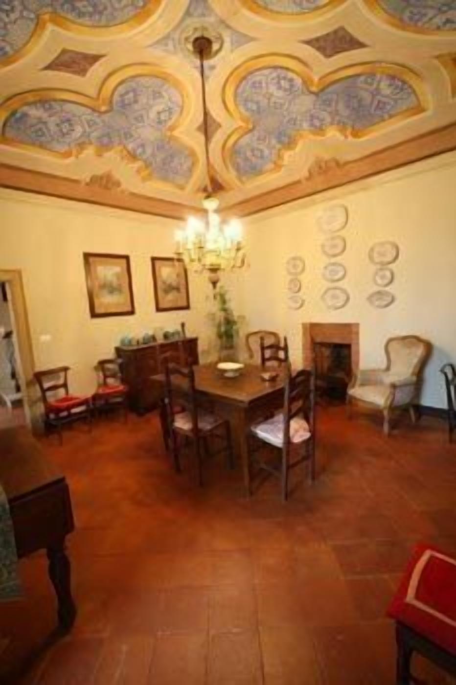 Comedor con mesa y sillas de madera, una lámpara de araña y techo con diseño.