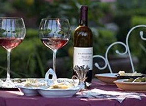 Una mesa servida con copas de vino, una botella y platos de comida.