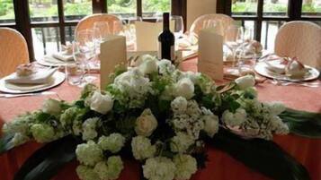 Mesa de jantar posta para quatro pessoas, com flores brancas no centro, rodeada por cadeiras.