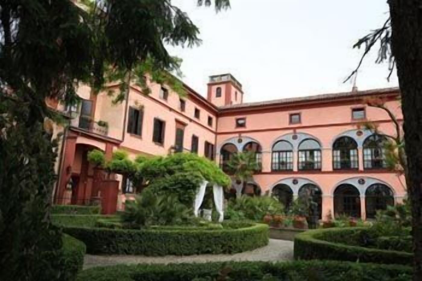 Ein Innenhof mit einem rosafarbenen Gebäude, das gewölbte Fenster und eine zentrale Fontäne zeigt.