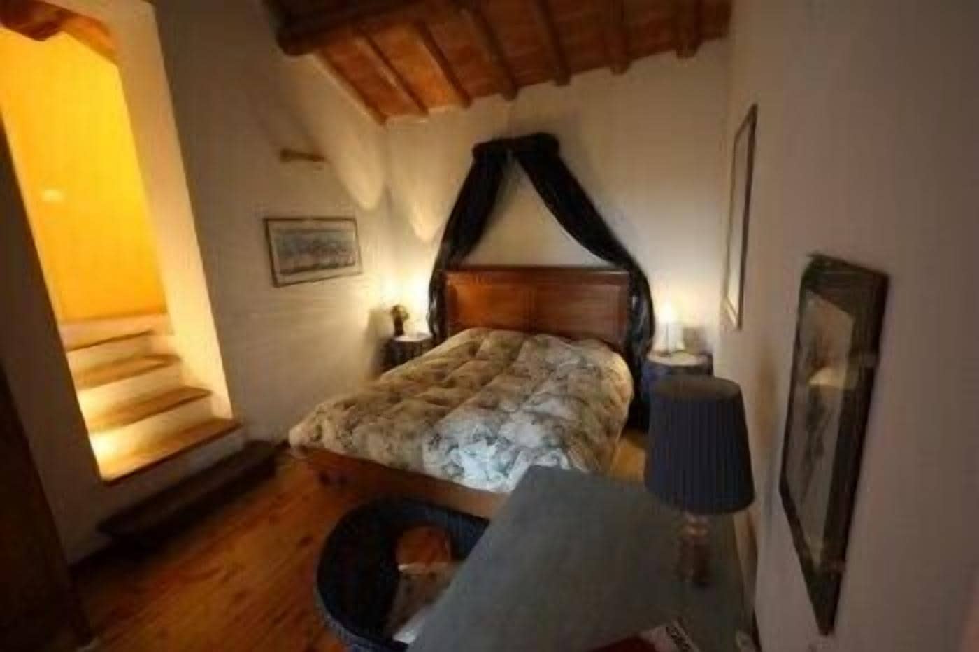 A bedroom with a wooden bed, a nightstand, a lamp, and a framed picture on the wall.