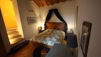 A bedroom with a wooden bed, a nightstand, a lamp, and a framed picture on the wall.