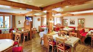 Un restaurante acogedor con interiores de madera, varias mesas de comedor y asientos con cojines rojos.