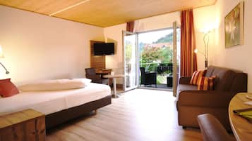 A hotel room with a bed, a sofa, a TV, a balcony with a view, and a wooden ceiling.