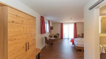 Una habitación de hotel con un armario de madera, una cama, un escritorio con una silla y una mesita.