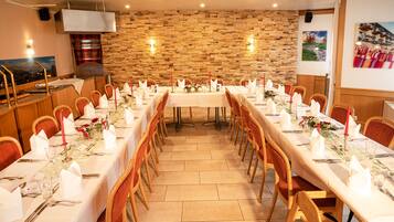 A long dining table set for a formal event with white tablecloths, red candles, and floral centerpieces.
