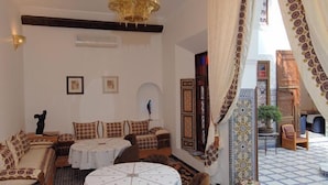A cozy interior with a chandelier, patterned cushions, and a tiled floor. - Riad Souafine (Fes)