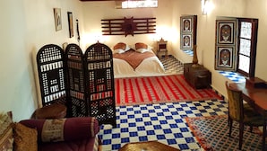 A traditional room with a checkered floor, a bed with a patterned bedspread, a wooden ceiling, and decorative wall panels. - Riad Souafine (Fes)