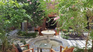 A courtyard with a fountain, seating area, and decorative tiles. - Riad Souafine (Fes)