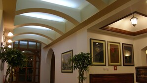 Un pasillo con una puerta de madera, obras de arte enmarcadas y plantas en macetas.