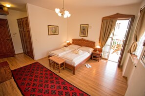 A bedroom with a double bed, bedside tables, a wooden bench, a red patterned rug, and a balcony with a view. - Boutique Hotel Old Town (Mostar)