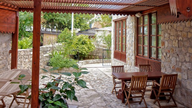 Un espacio de estar al aire libre con techo, paredes de piedra y mobiliario de madera.