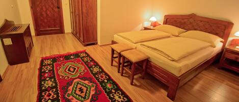 Une chambre à coucher avec un lit en bois, deux tables de chevet avec des lampes, une armoire en bois et un tapis à motifs.
